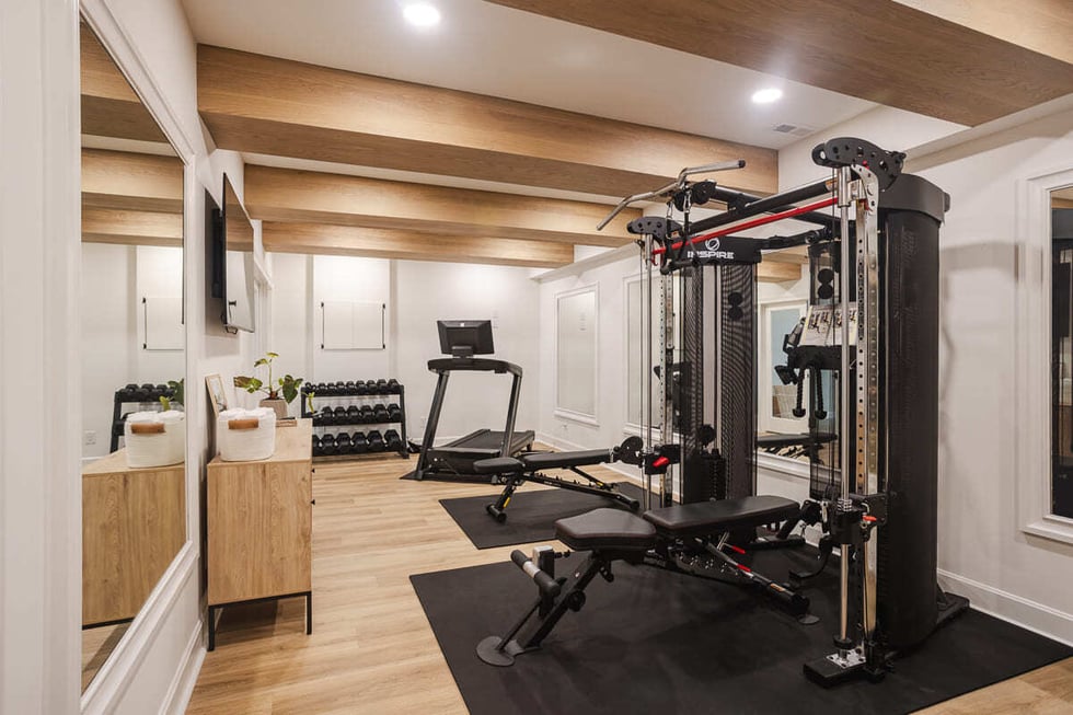 Bright fitness room with strength training equipment, wall mirrors, and wood beam ceiling, located in Cincinnati