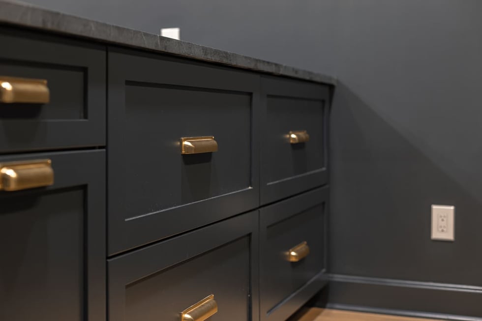 Close-up of navy built-in bar drawers with brass pulls and stone countertop in a Cincinnati basement remodel