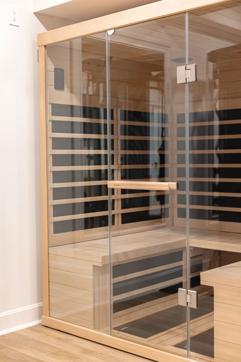 Glass-front infrared sauna with wood interior in a Cincinnati home wellness and fitness space