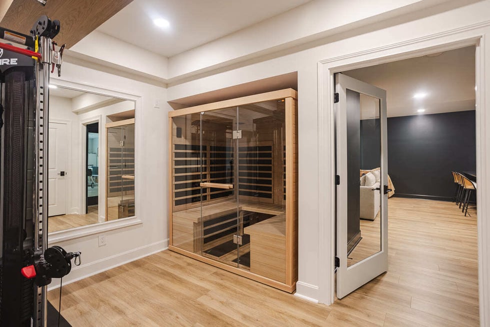 Infrared sauna next to home gym with glass door and wood floors, located in Cincinnati