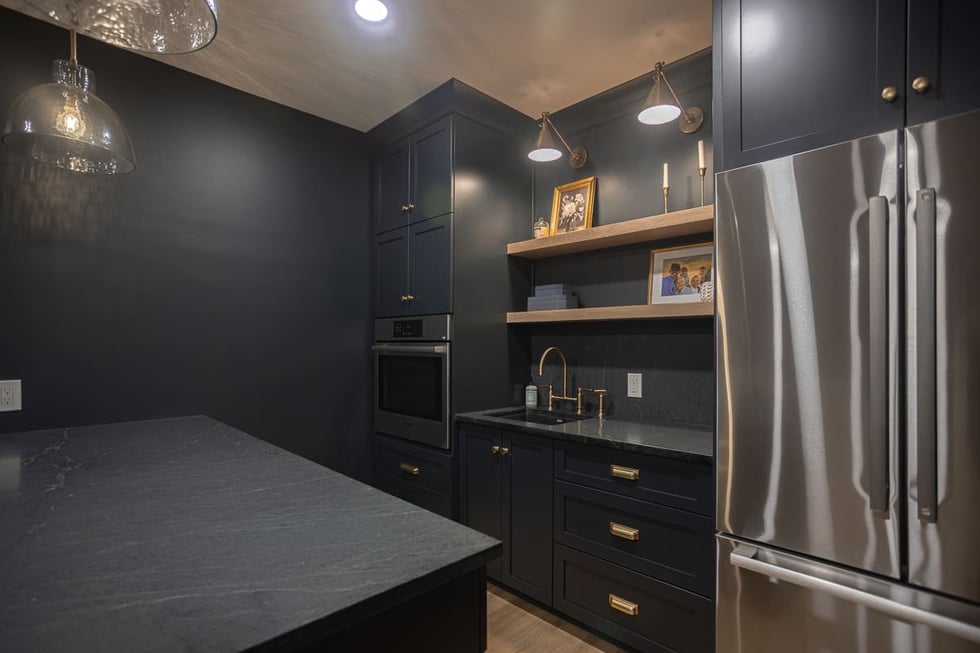 Sleek basement kitchenette with dark cabinets, stainless appliances, open shelving, and brass fixtures in a Cincinnati home