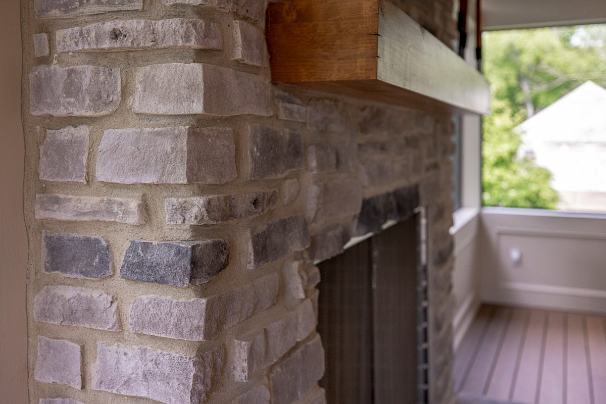 Close-up of a stone fireplace with wood mantel in a screened porch in Greater Cincinnati
