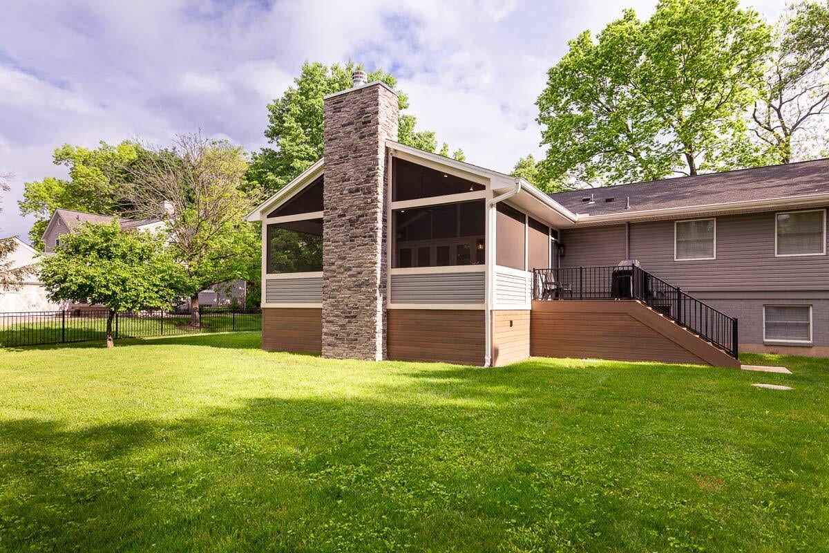Screened-in porch with stone fireplace and staircase in Cincinnati area backyard