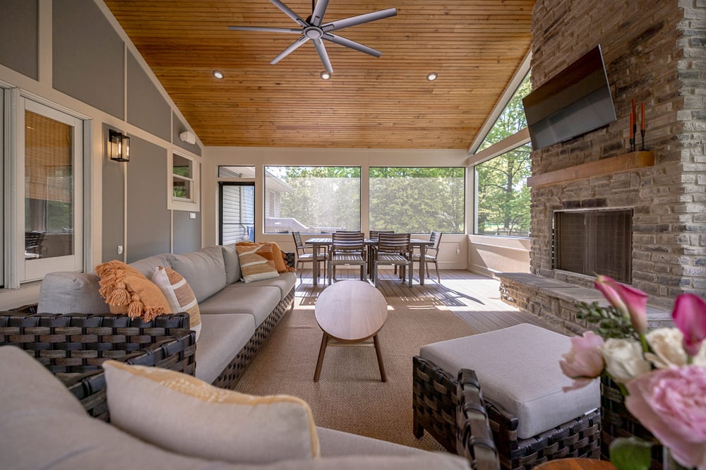 Screened-in porch with wood ceiling, stone fireplace, and dining area in the Cincinnati area
