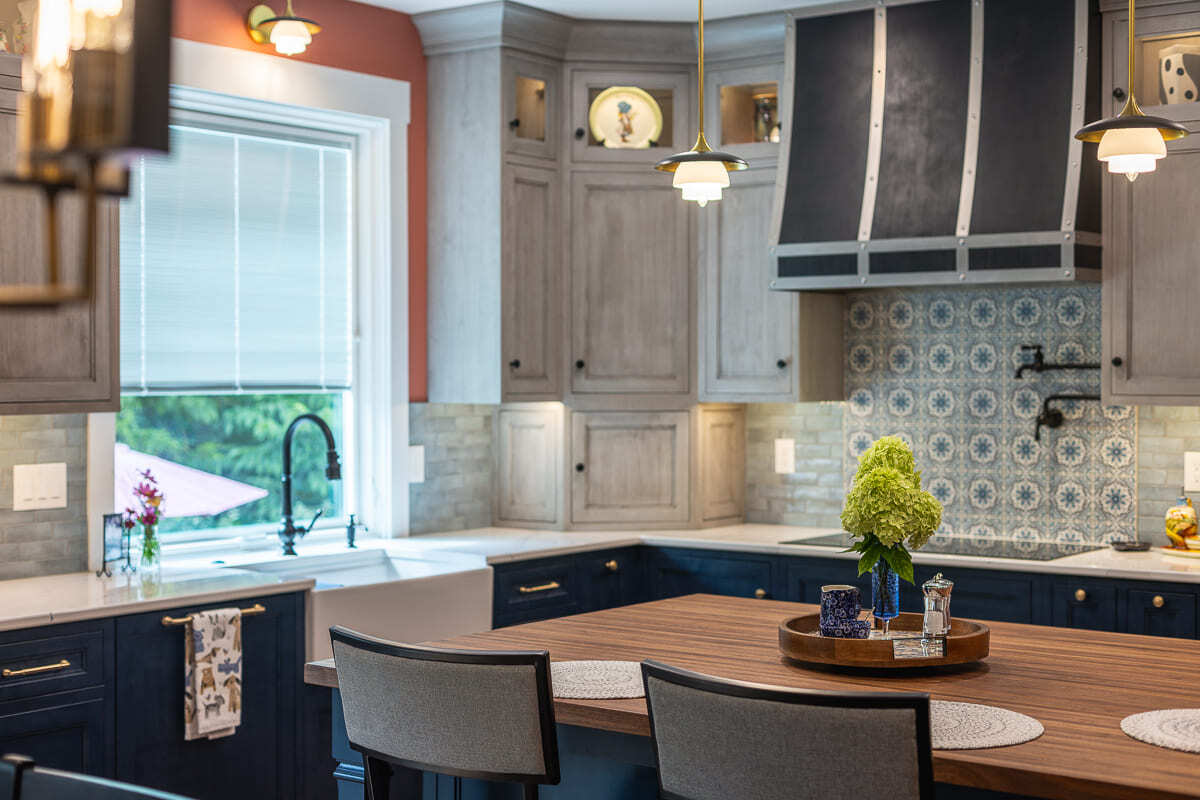 Amish-built kitchen cabinets with wood island top, farmhouse sink, patterned tile, and custom range hood.