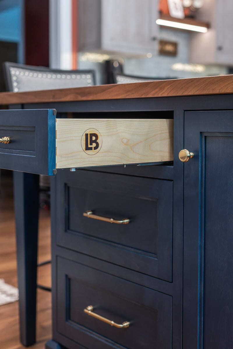 Close-up of Amish-built kitchen island drawer with Legacy Builders Group detail and brass hardware. Close-up of Amish-built kitchen island drawer with Legacy Builders Group detail and brass hardware.