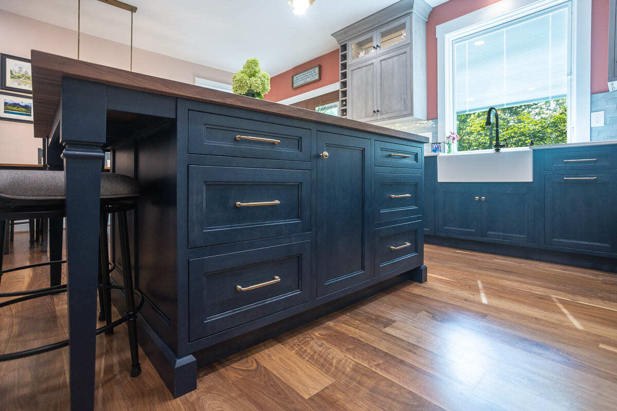 Custom Amish-built kitchen island with blue cabinetry, wood top, farmhouse sink, and warm wood floors.