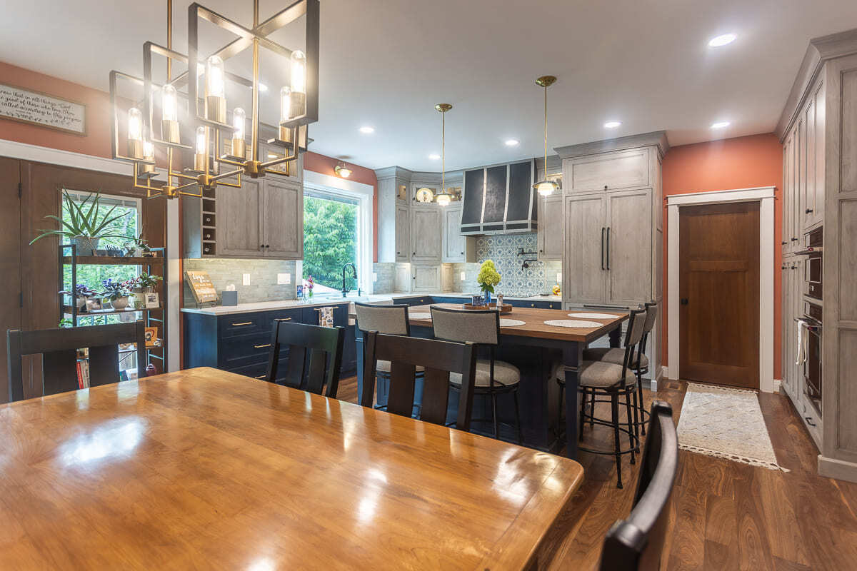 Remodeled kitchen with Amish-built cabinetry, large island seating, statement lighting, and dining area.