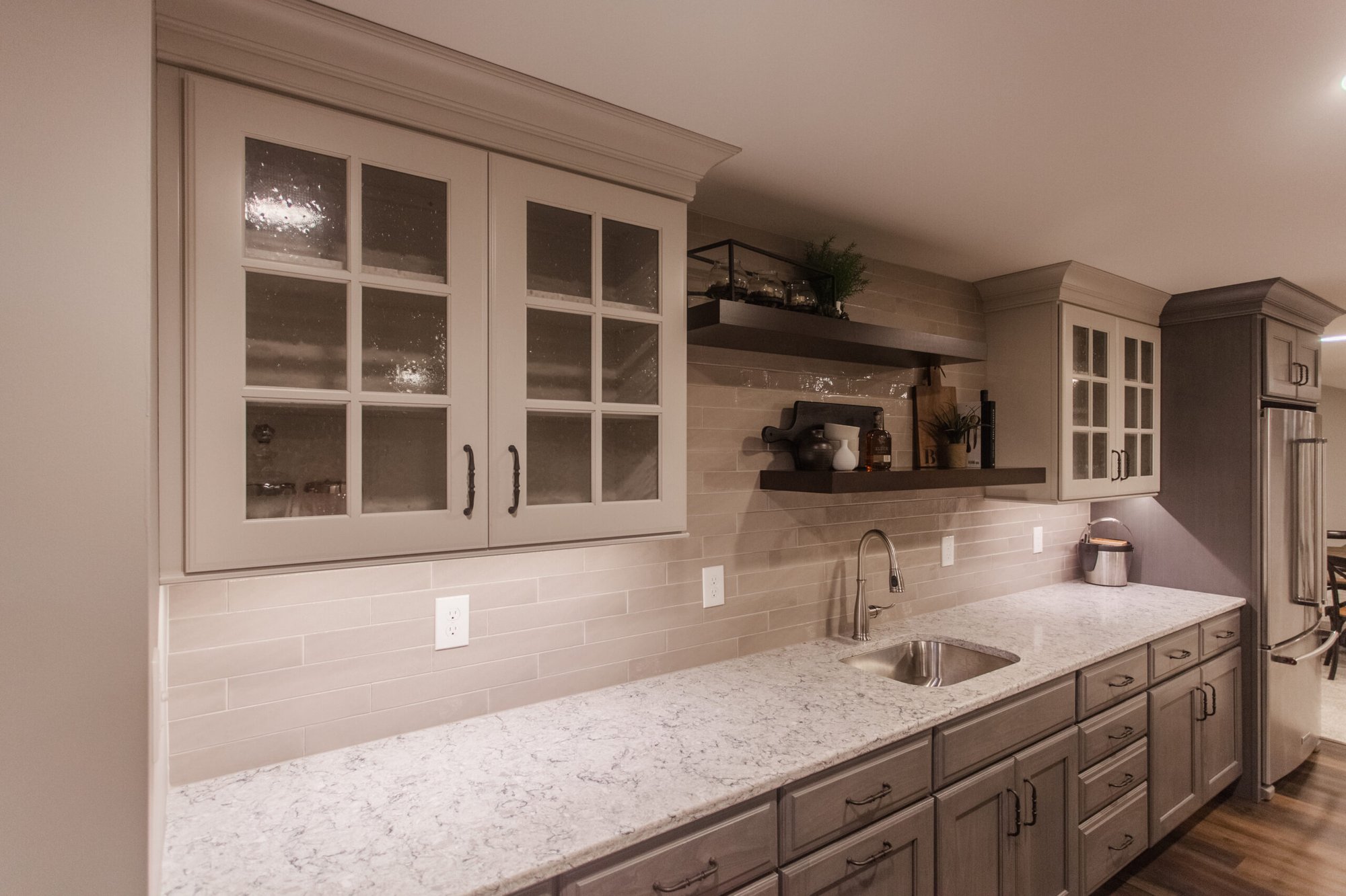 Amberly Village, OH basement wet bar with glass cabinets, floating shelves, sink, and marble-look counters