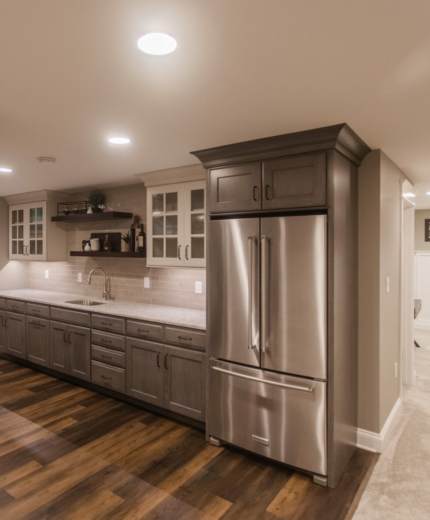 Amberly Village, OH basement wet bar with stainless fridge, sink, glass cabinets, and marble-look counters