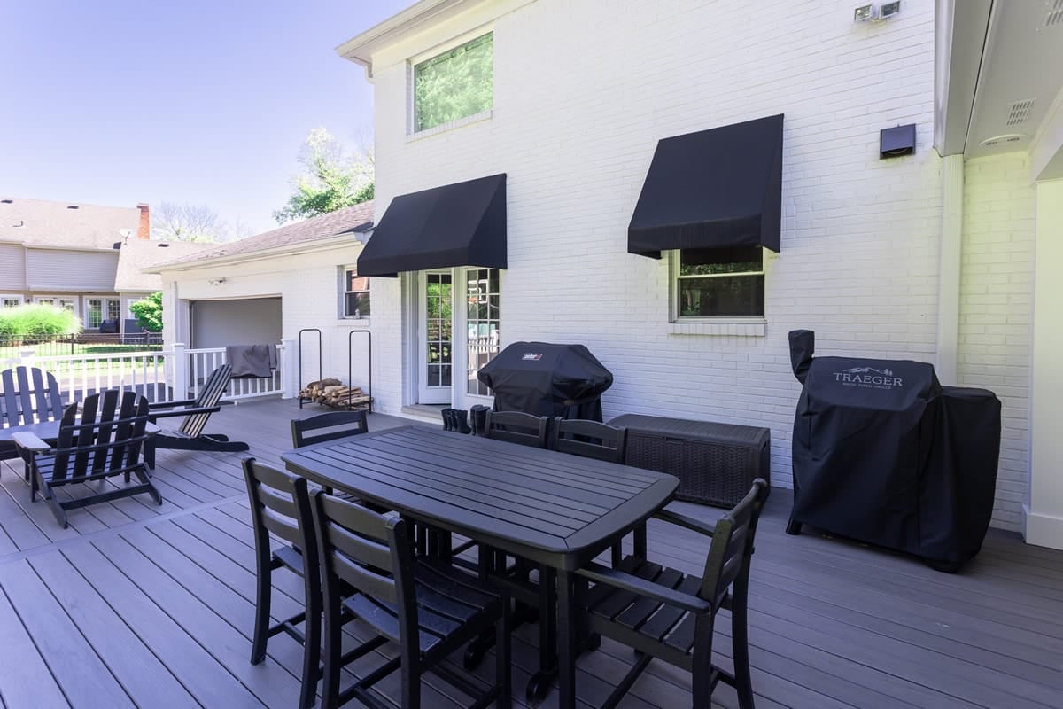 Backyard deck space on sunny day with black patio furniture on home remodel
