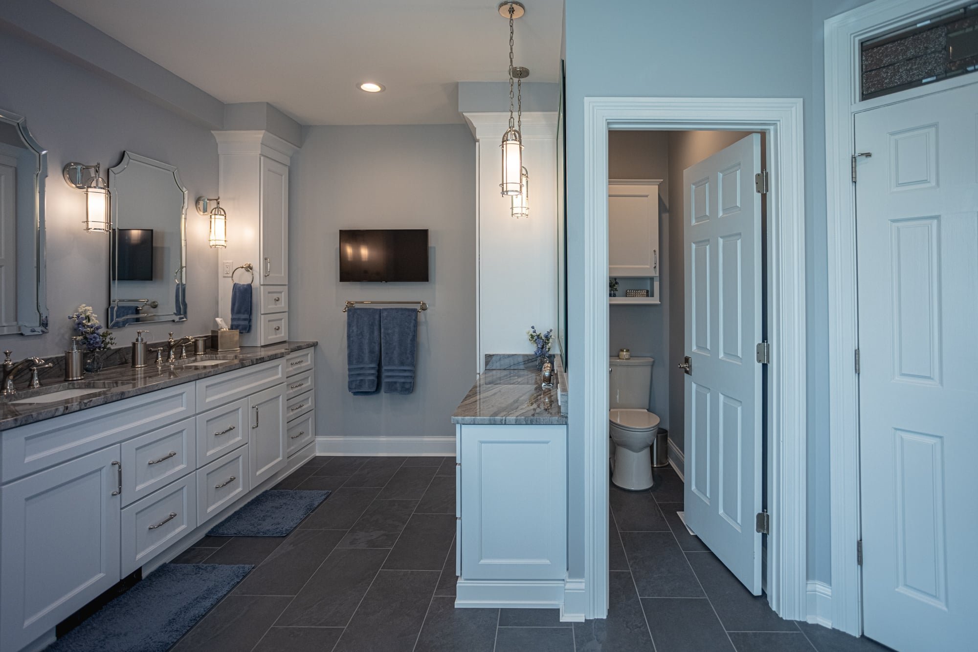 Bathroom with double vanity, TV, and private toilet room by Legacy Builders Group in Greater Cincinnati