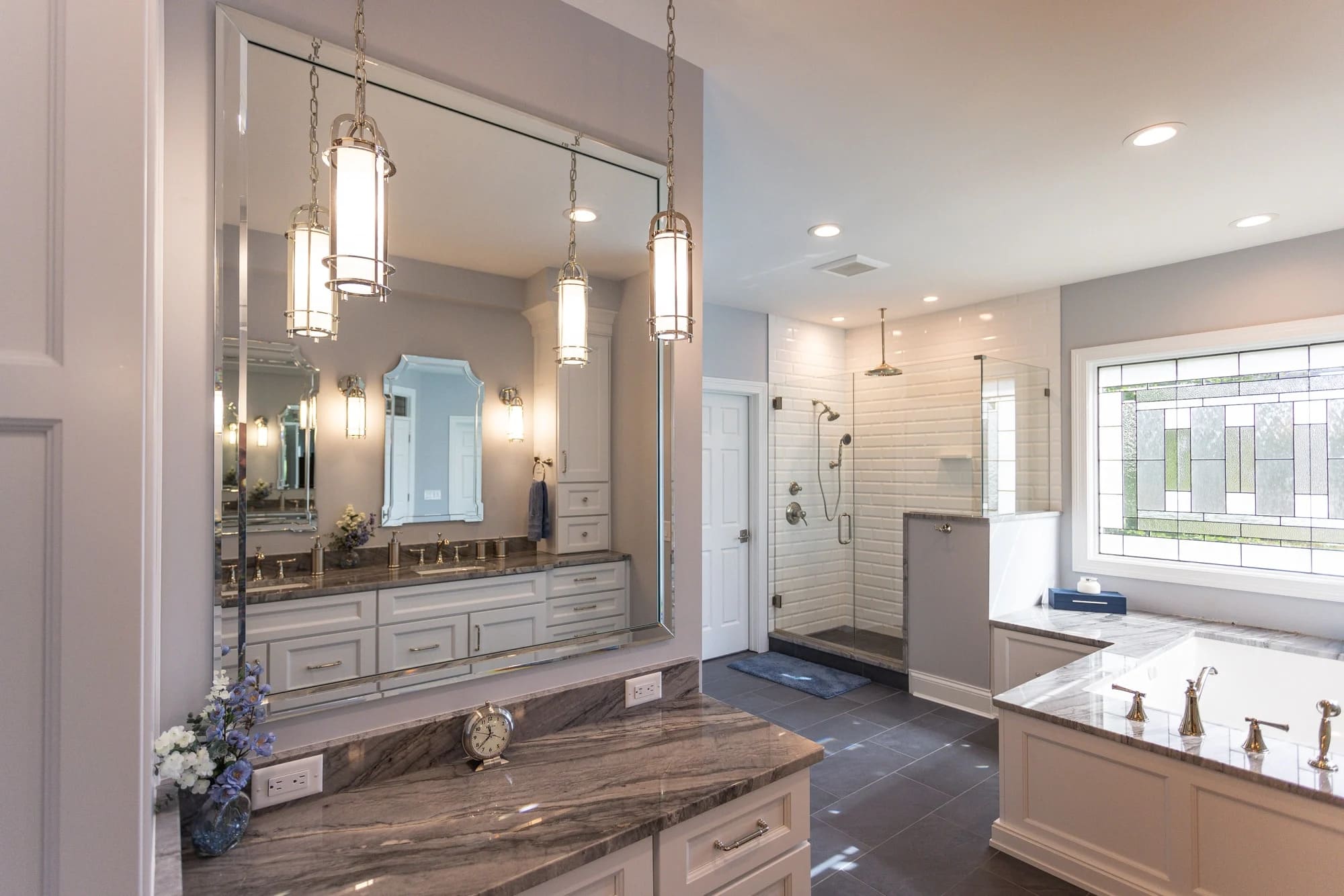 Bathroom with double vanity, large mirror, glass shower, and soaking tub by Legacy Builders Group in Greater Cincinnati