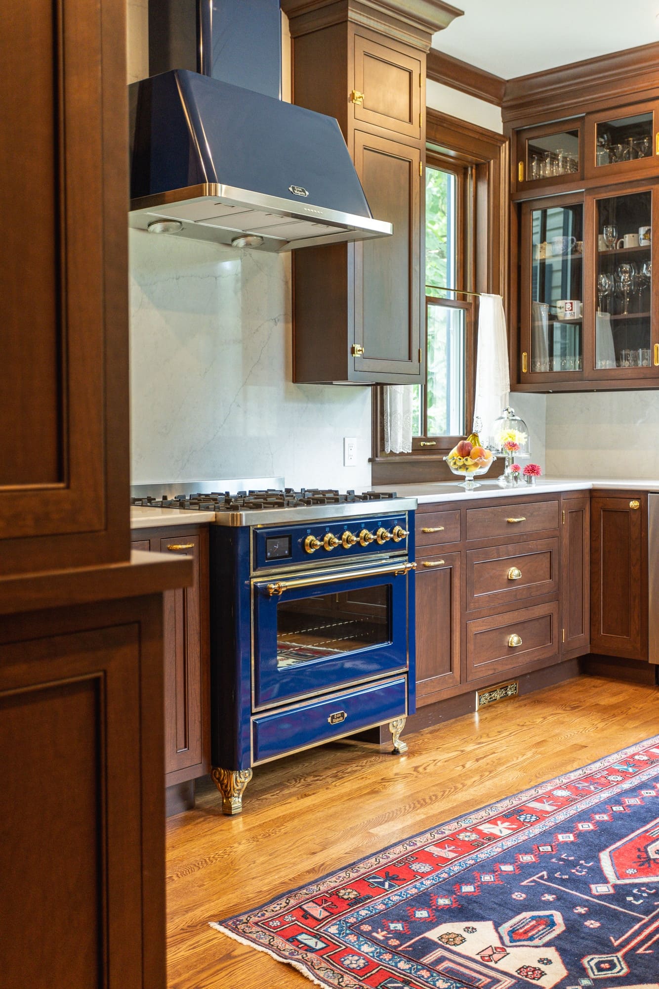 Blue statement range with brass accents and glass-front cabinetry in a custom Greater Cincinnati kitchen