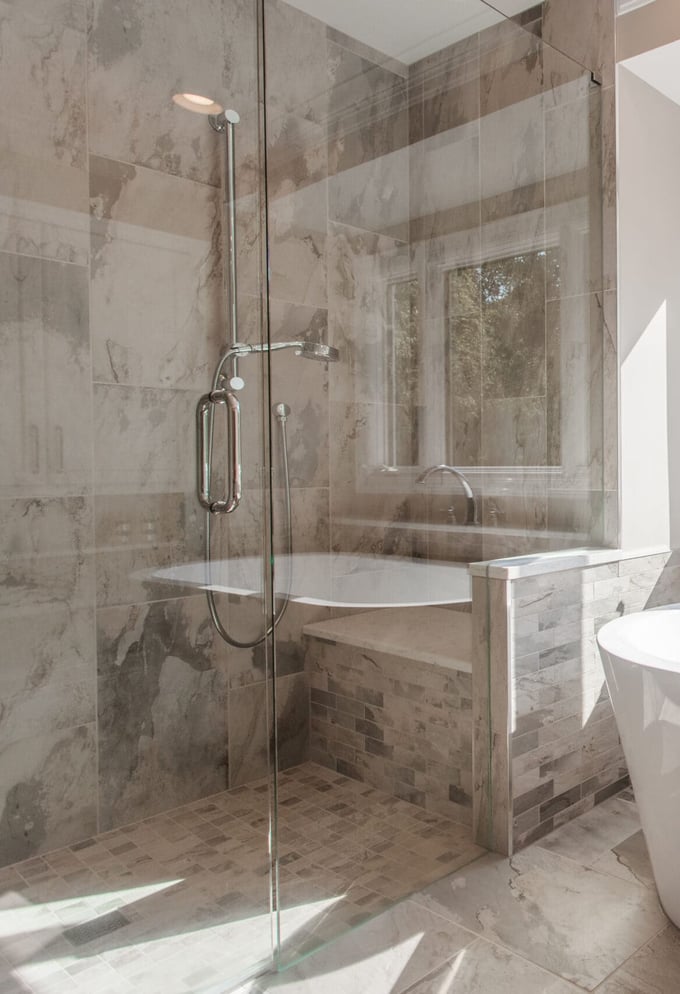 Bright Cincinnati bathroom with freestanding tub, walk-in shower, and large window with wooded view