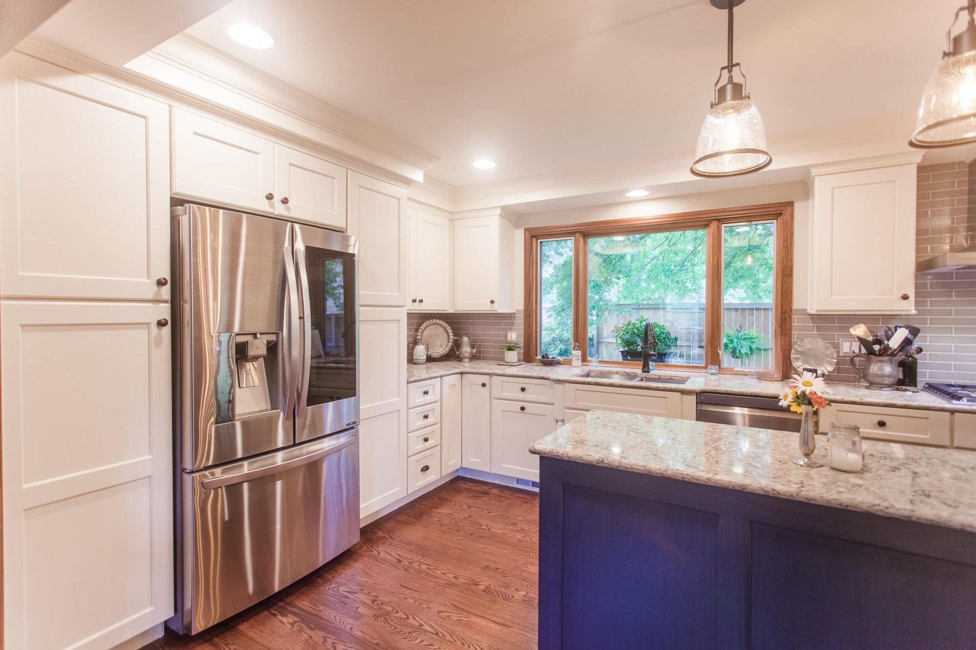 Bright kitchen with white cabinets, stainless appliances, granite island, and wood floors in a Cincinnati home