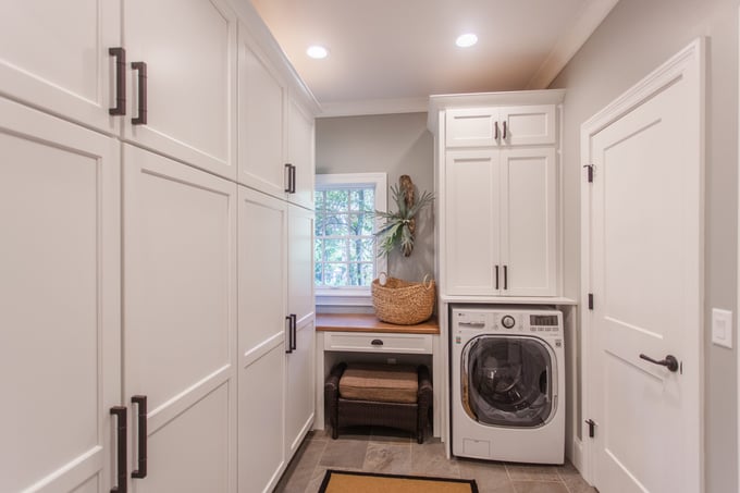 Bright laundry room with white cabinets, built-in storage, and front-load washer located in Cincinnati