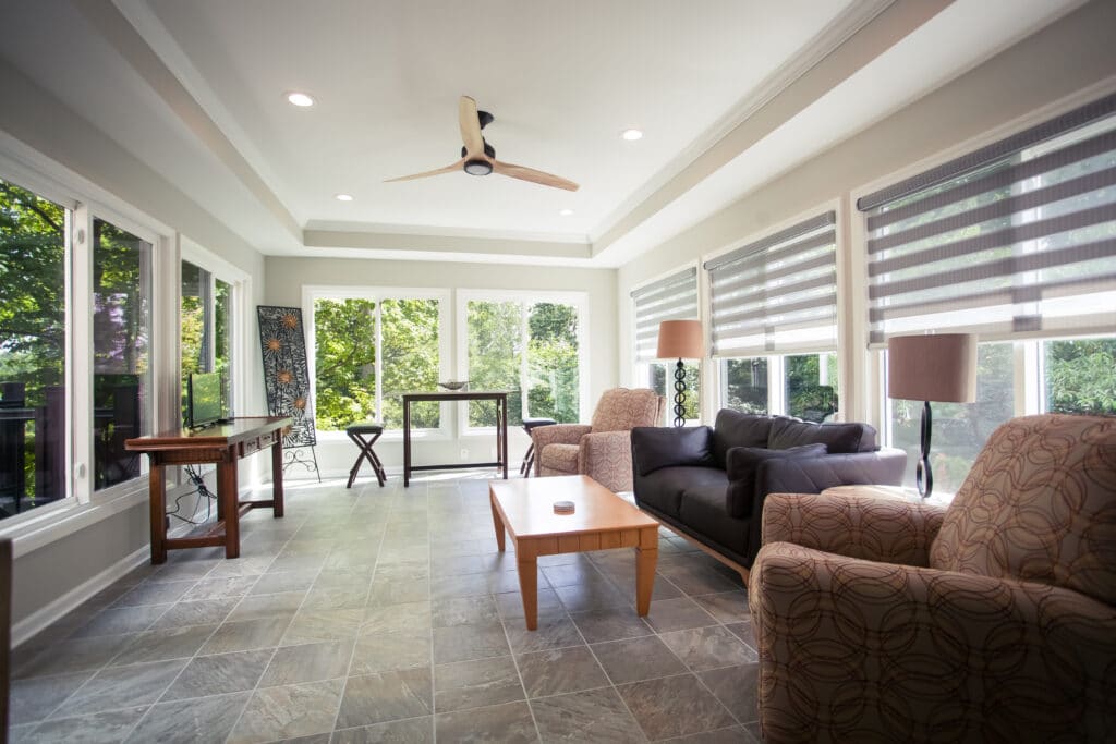 Bright sunroom home addition with large windows, tile floors, and modern seating located in Cincinnati