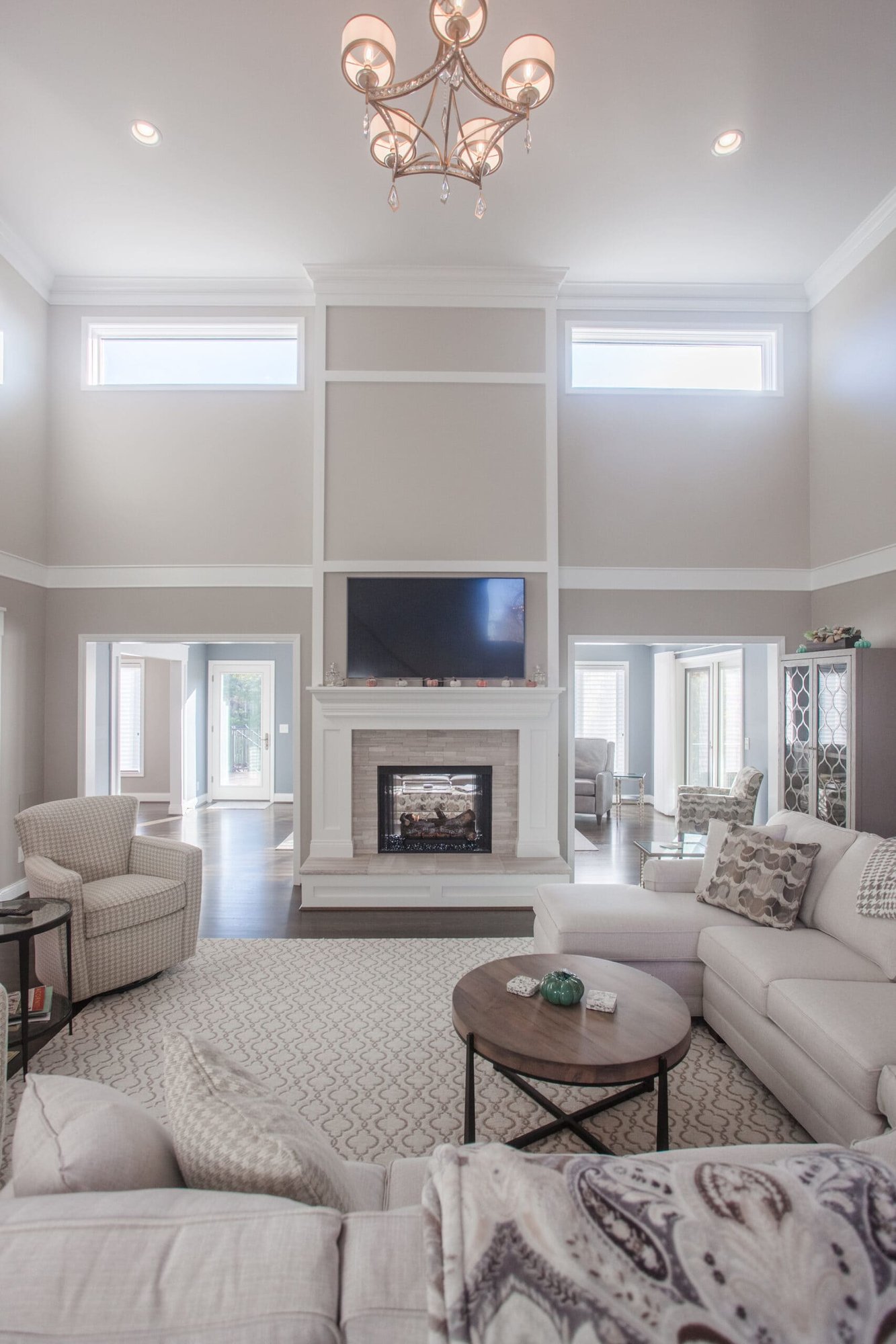 Bright two-story living room with fireplace, chandelier, neutral seating, and tall windows in Cincinnati, OH