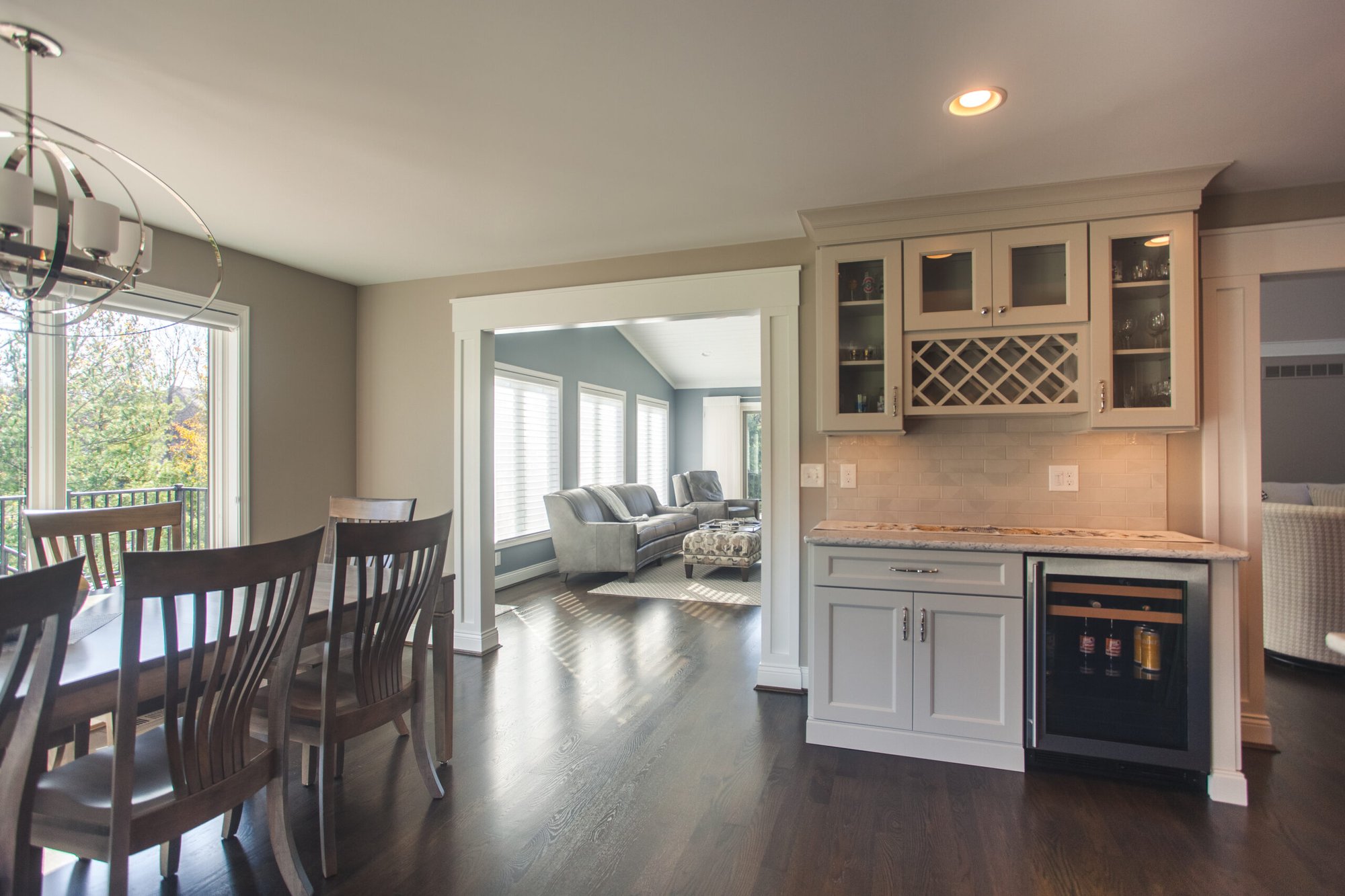 Cincinnati dining area with wood table, built-in bar cabinet, wine fridge, and open view to living room with hardwood floors