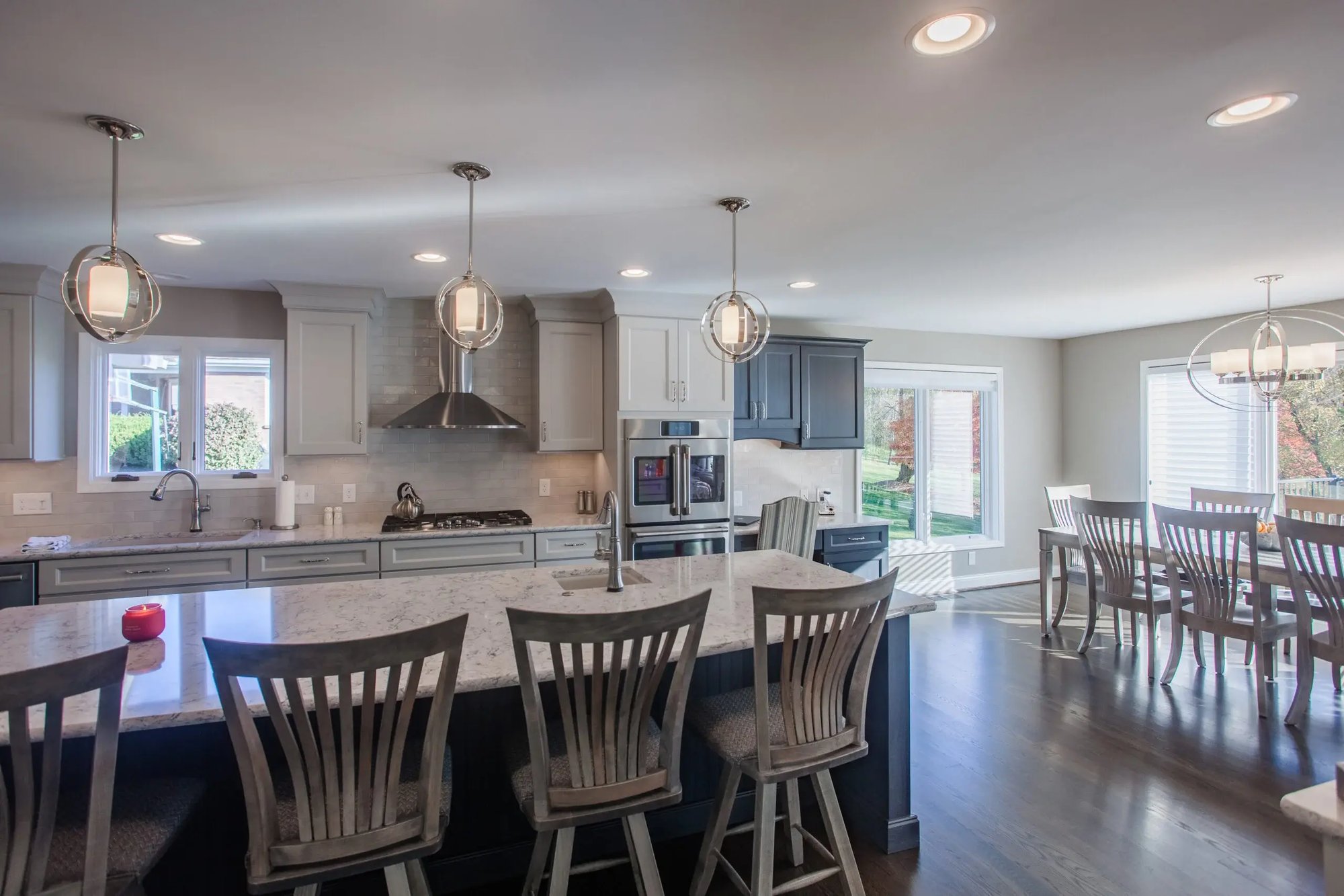 Cincinnati kitchen with large island, pendant lighting, white cabinetry, bar seating, and open dining area with hardwood floors