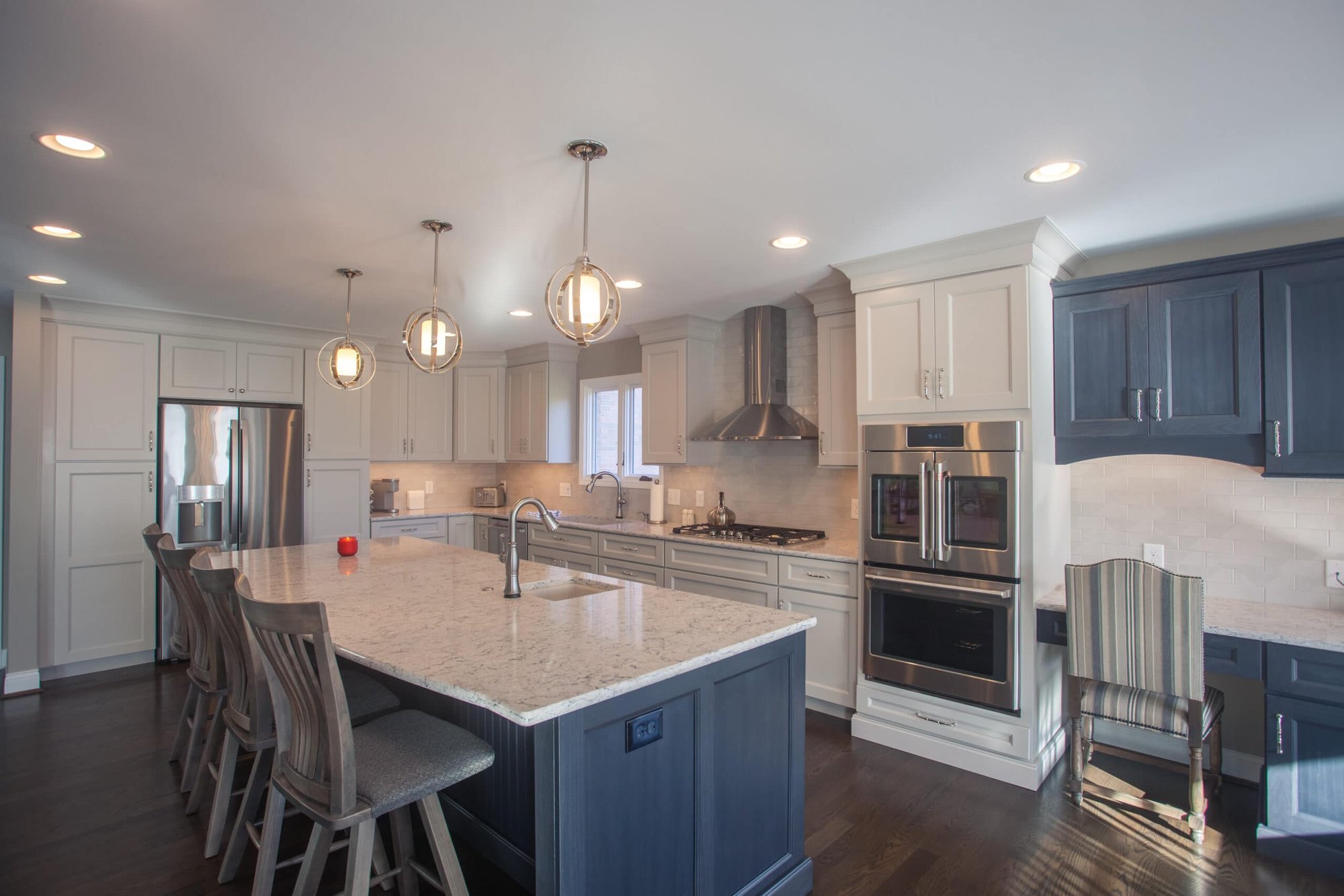 Cincinnati kitchen with large island, white and blue cabinetry, pendant lights, stainless appliances, and hardwood floors in an open layout
