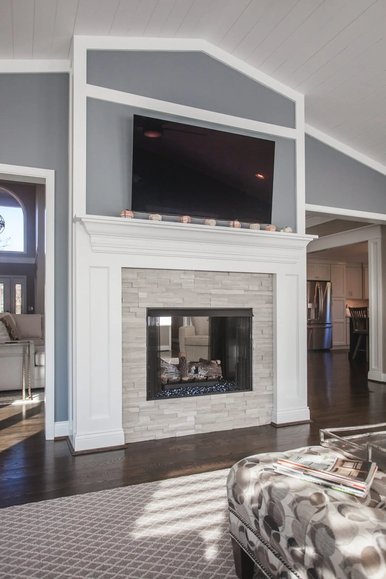 Cincinnati living room with fireplace, wall-mounted TV, gray walls, and hardwood floors in a bright, open-concept space