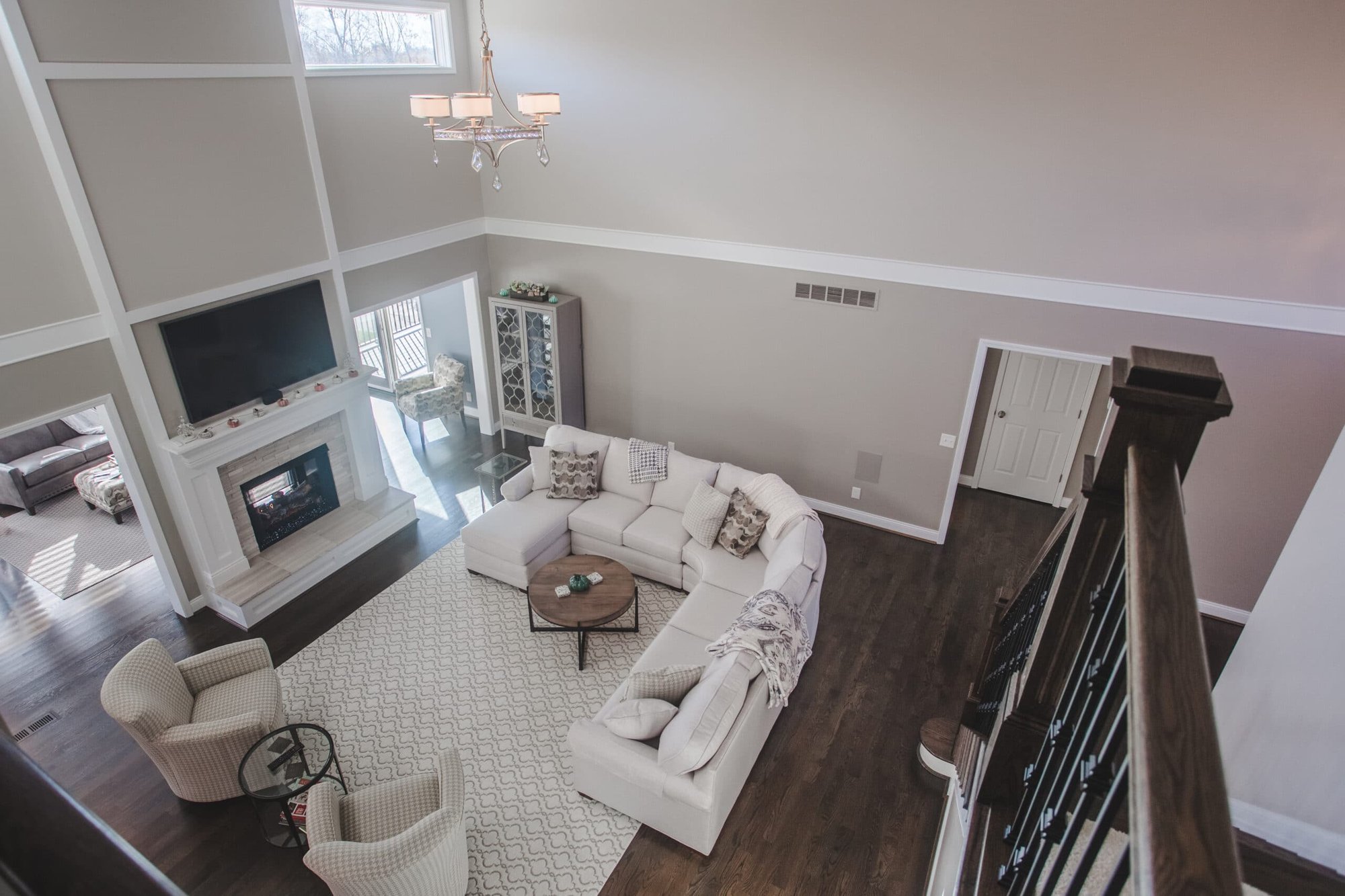 Cincinnati living room with high ceilings, white sectional sofa, fireplace, chandelier, and hardwood floors viewed from an upper level