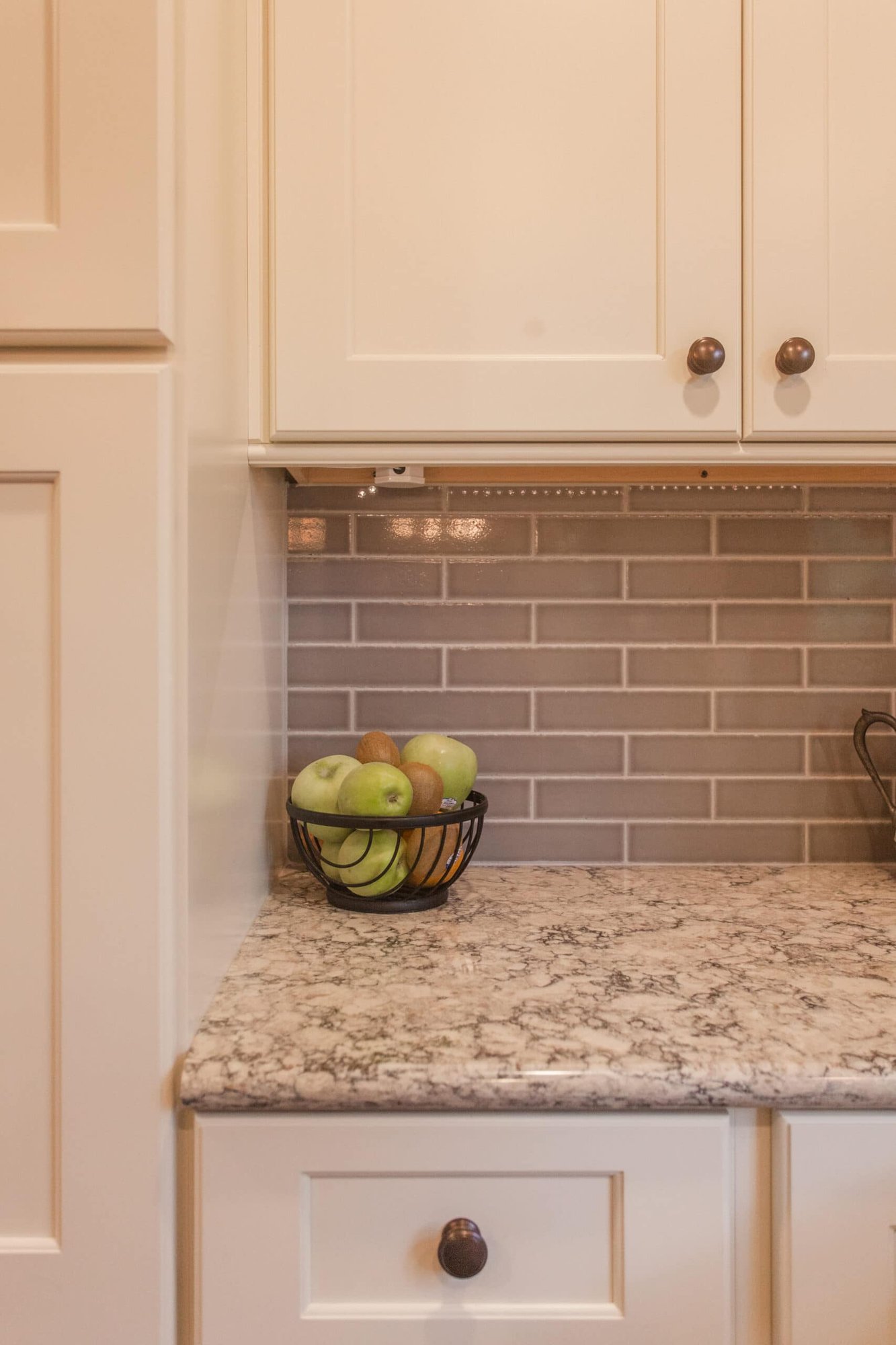 Close-up of granite countertop, white cabinets, and gray subway tile backsplash in a Cincinnati kitchen