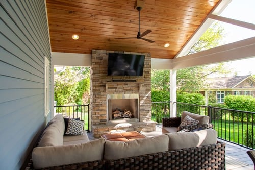 Covered outdoor living space in Greater Cincinnati with fireplace, TV, and cozy seating