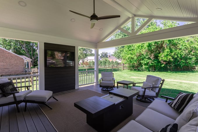 Covered patio with modern outdoor furniture, ceiling fan, and TV overlooking a backyard located in Cincinnati