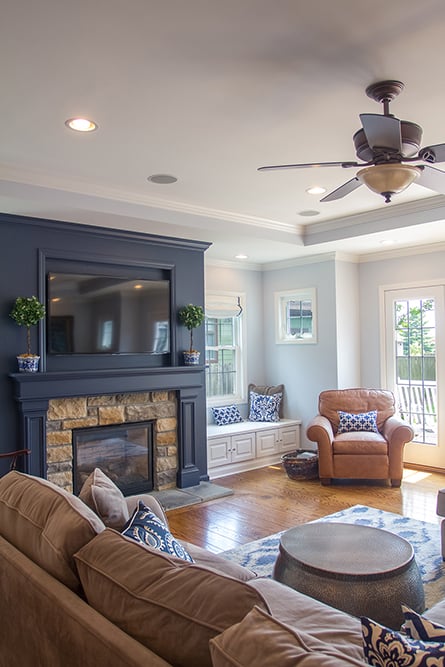 Cozy living room home addition with stone fireplace, navy accent wall, and natural light located in Greater Cincinnati