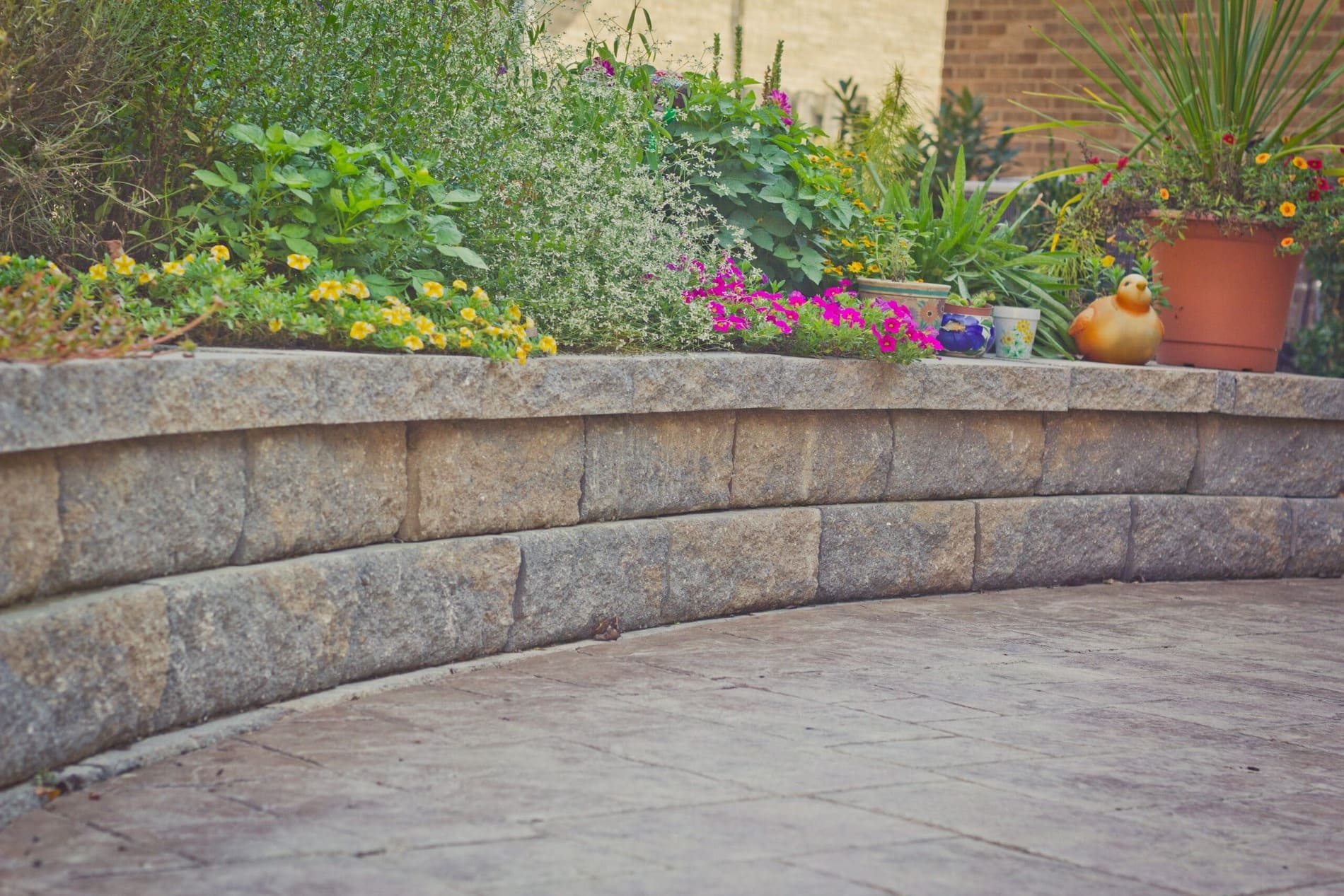 Curved stone retaining wall with patio and colorful plantings by Legacy Builders Group in Greater Cincinnati