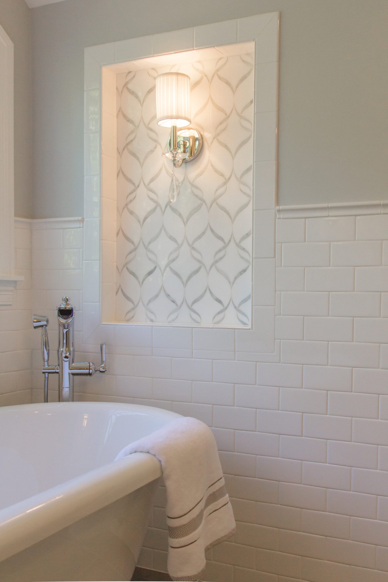 Decorative Cincinnati bathroom with a freestanding tub, wall niche light, and elegant white subway tile