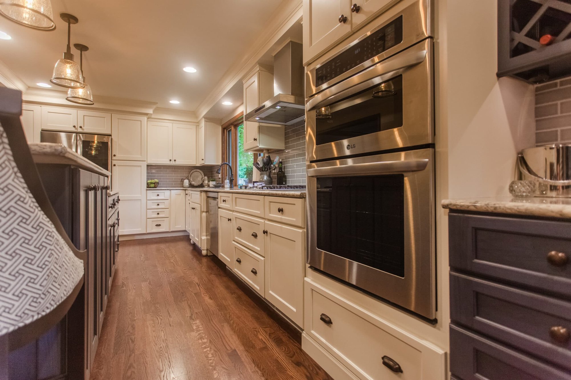 Galley-style kitchen with white cabinetry, double wall ovens, stainless appliances, and wood floors in Cincinnati