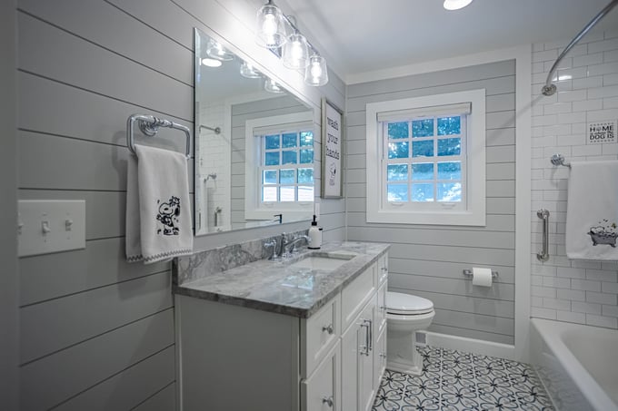 Gray bathroom remodel with mosaic tile flooring and tub and shower combo by Legacy Builders