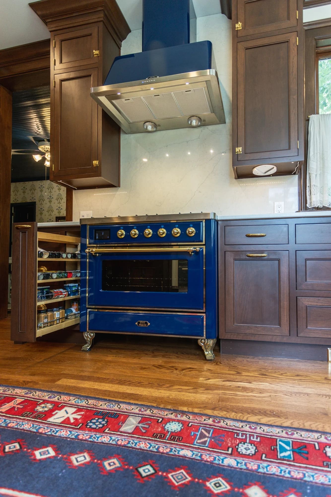 Greater Cincinnati kitchen featuring a bold blue range, custom vent hood and open pull-out spice storage