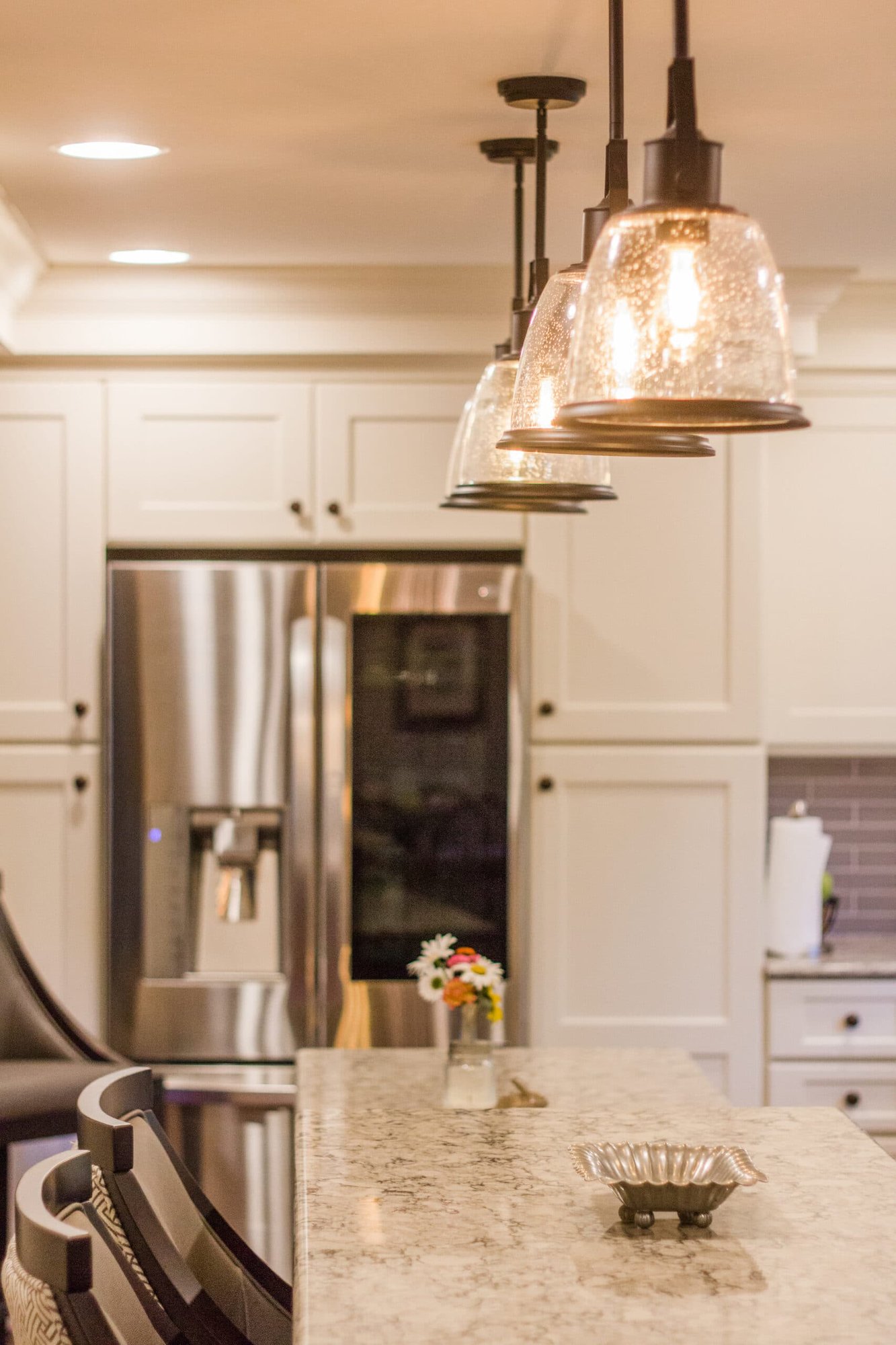 Kitchen island with granite countertop, pendant lighting, and stainless refrigerator in a Cincinnati home