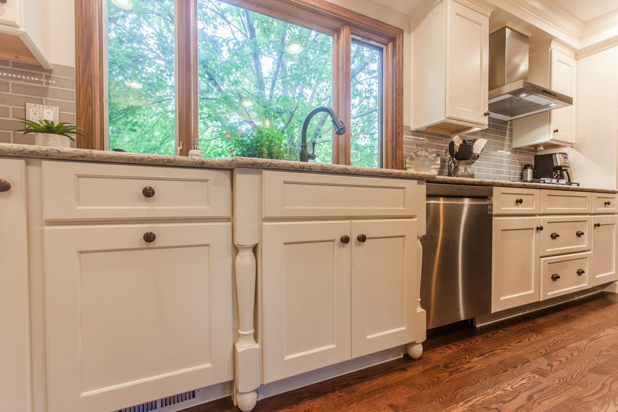 Kitchen sink wall with white cabinetry, granite counters, stainless dishwasher, and large window in a Cincinnati home