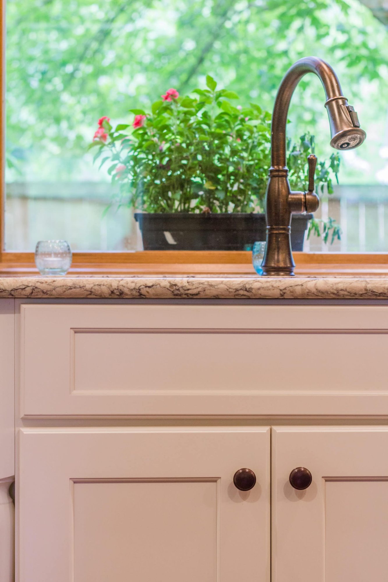Kitchen sink with granite countertop, bronze faucet, and window overlooking greenery in a Cincinnati home