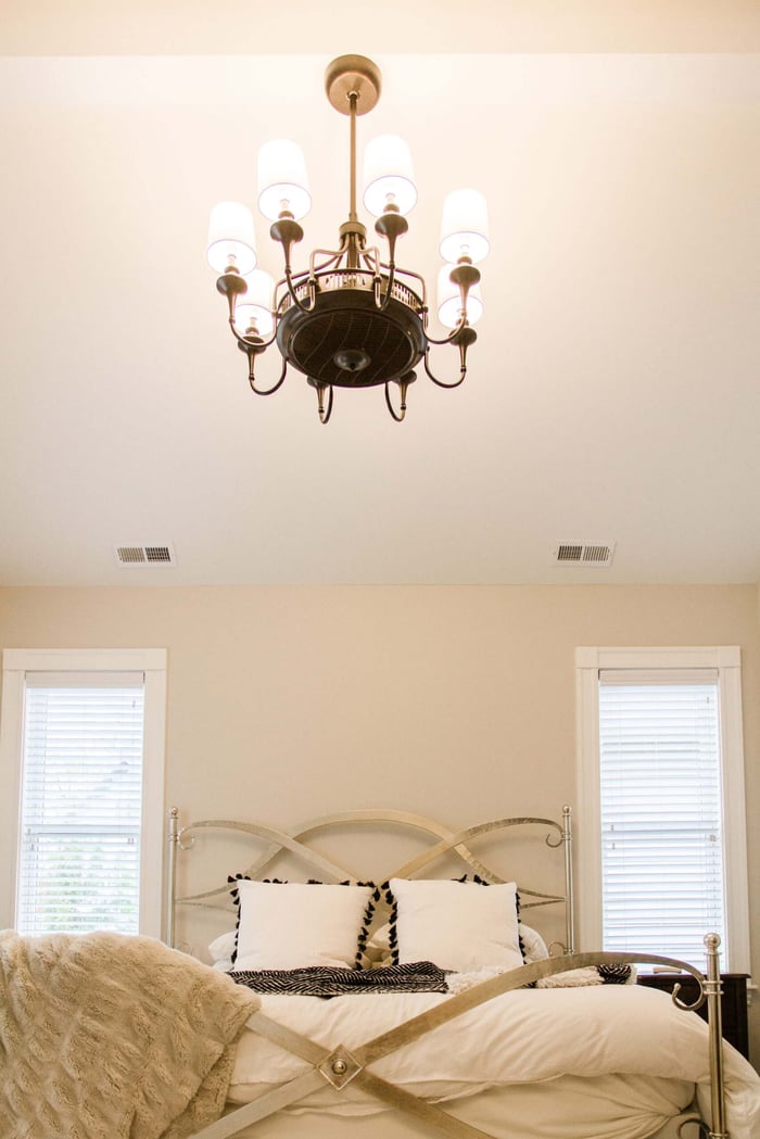 Master suite addition with bedroom below chandelier light by Legacy Builders