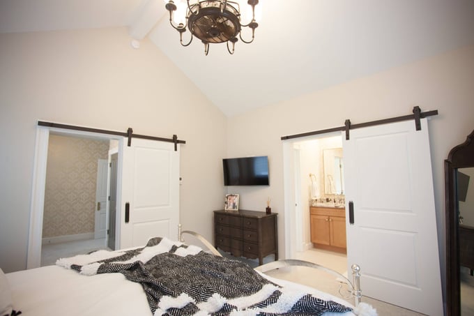 Modern master bedroom with barn doors, neutral decor, and connected bathroom located in Cincinnati