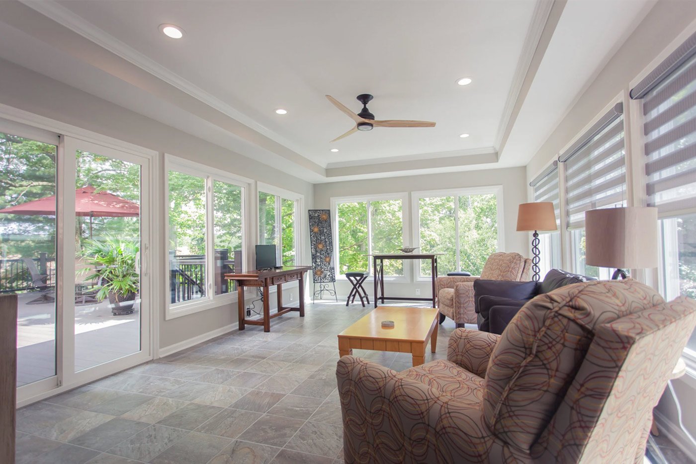 Modern sunroom with tile flooring, tray ceiling, and large windows by Legacy Builders in Cincinnati