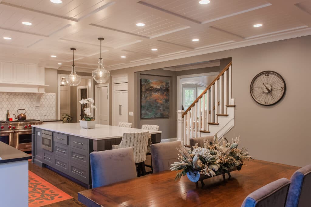 Montgomery, OH dining area and kitchen with gray island, glass pendants, coffered ceiling, and stairway