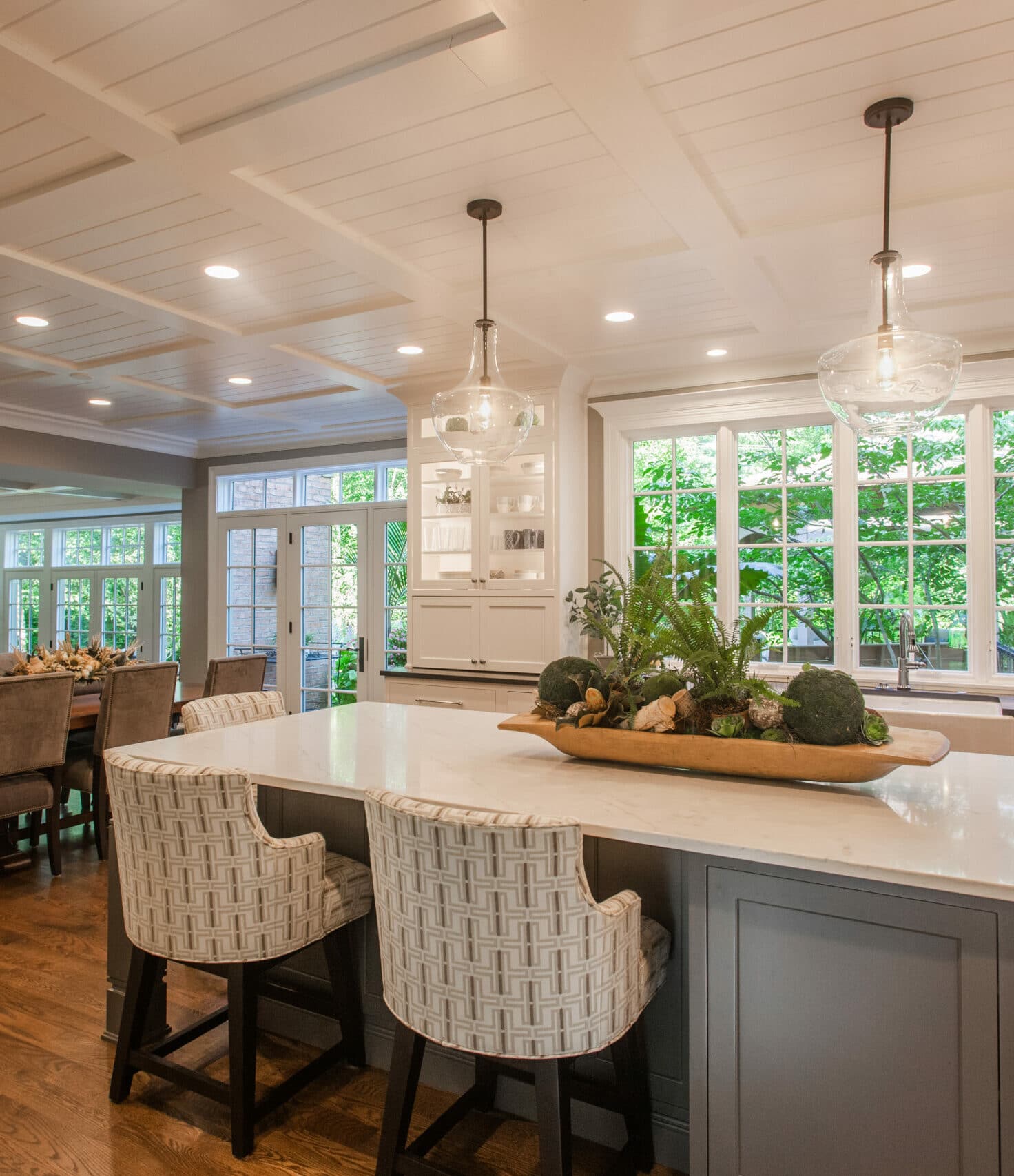 Montgomery, OH kitchen island with woven stools, glass pendant lights, coffered ceiling, and large windows