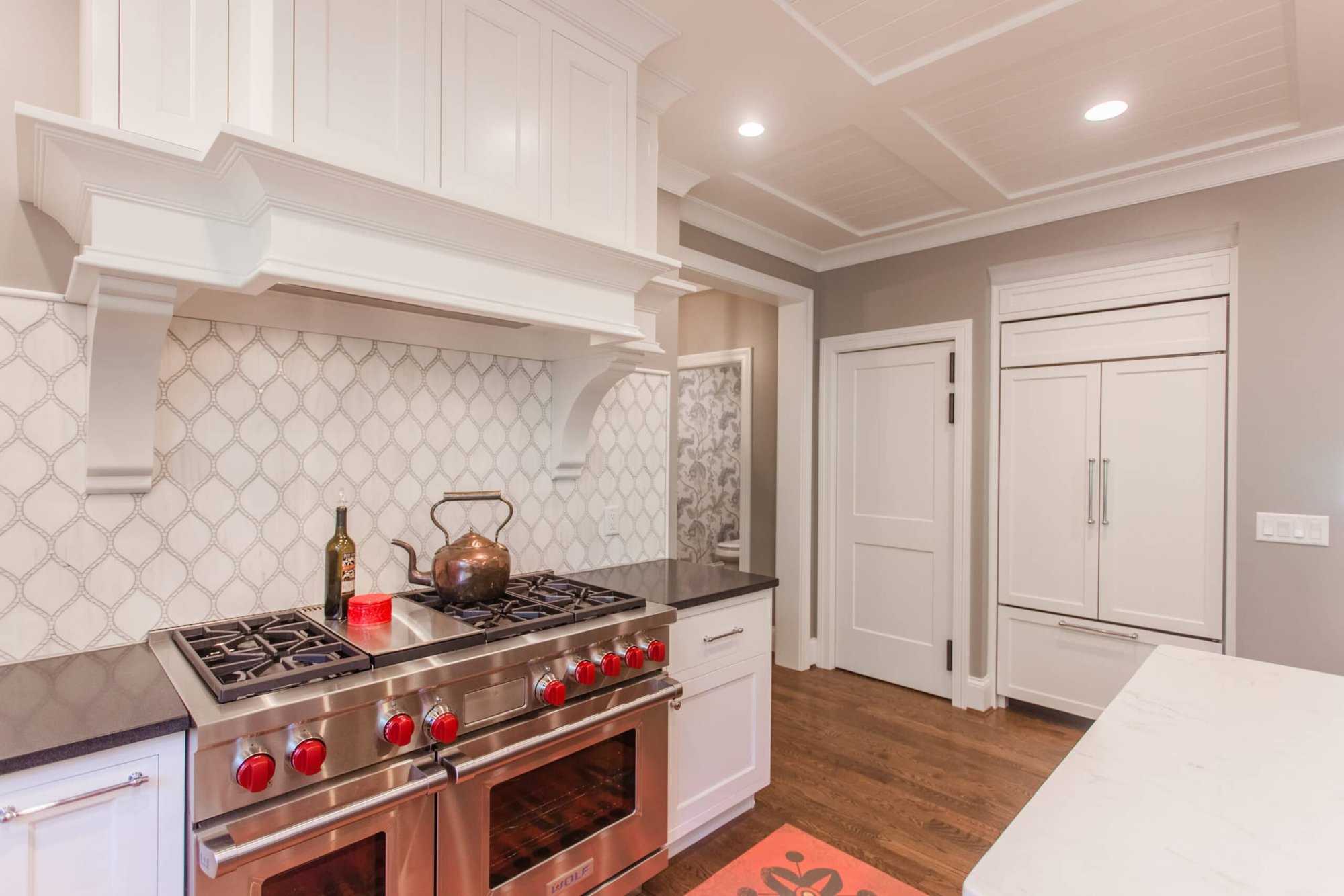 Montgomery, OH kitchen with pro-style range, white hood, patterned tile backsplash, and built-in fridge