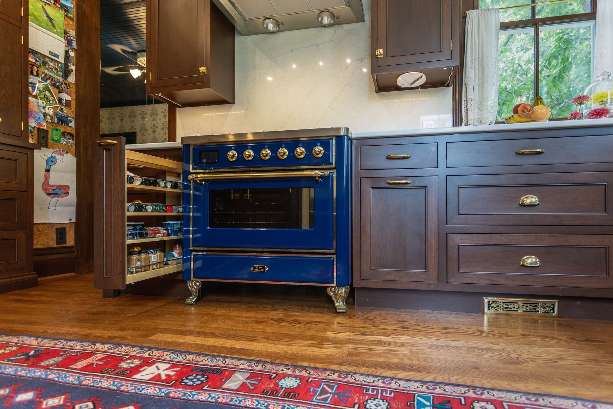 Pull-out spice storage beside a blue range and dark wood cabinetry in a Greater Cincinnati kitchen
