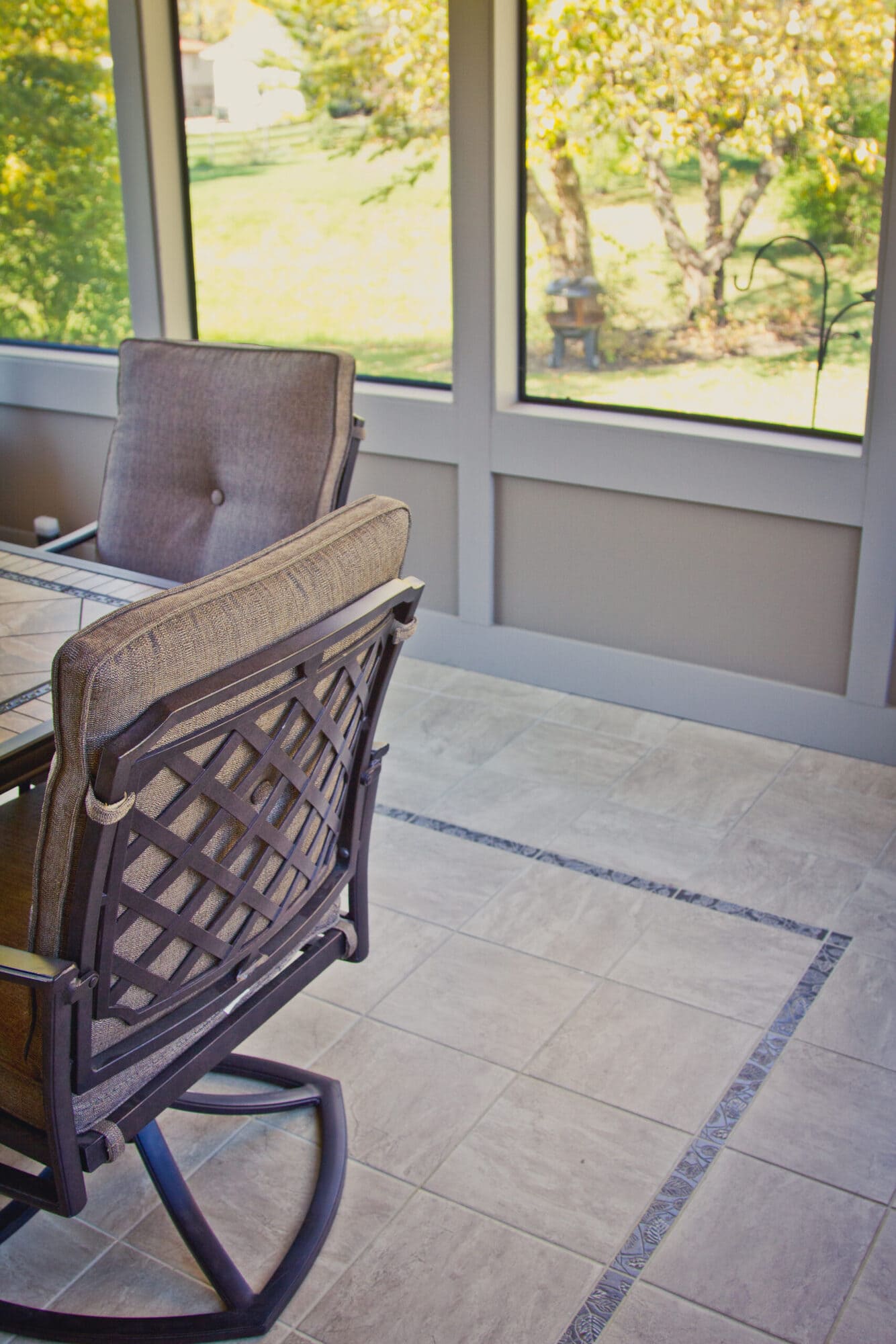 Screened porch interior with cushioned chair and tile flooring by Legacy Builders Group in Greater Cincinnati