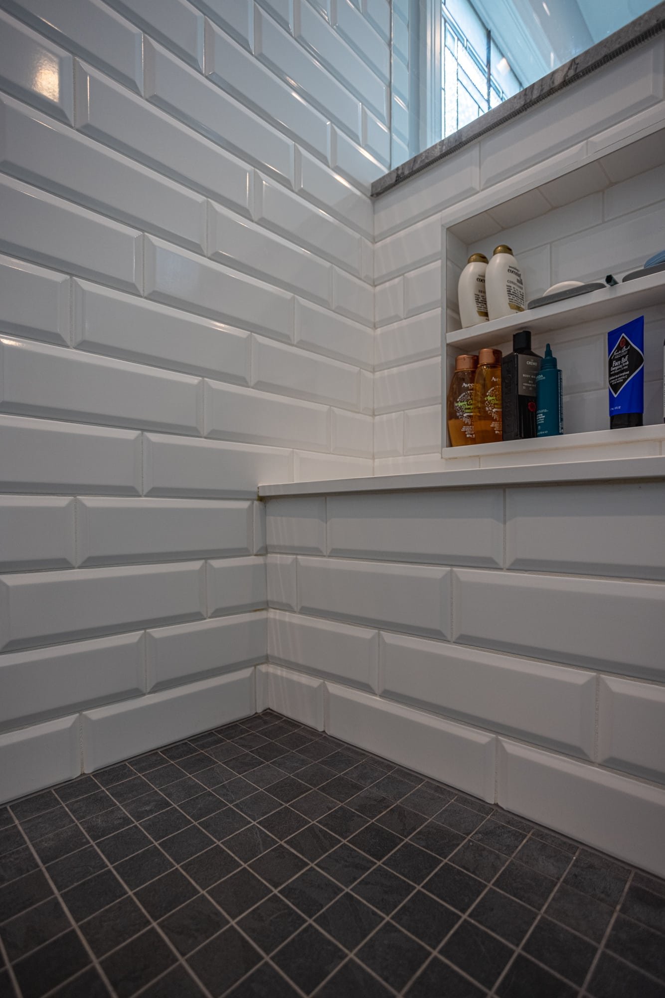 Shower corner with white subway tile, bench seat, and niche storage by Legacy Builders Group in Greater Cincinnati