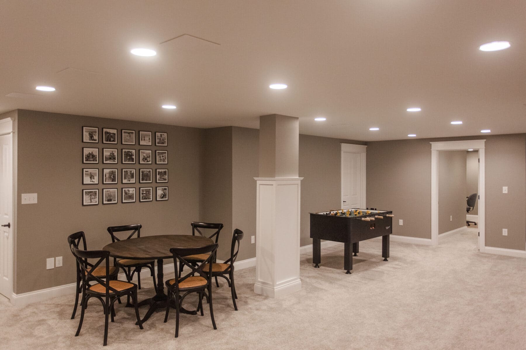 Spacious Cincinnati basement with game table, foosball, and family photo wall, designed for relaxation and entertainment
